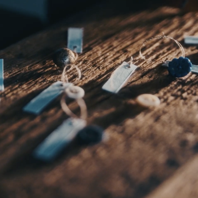 Guziki z przyczepionymi do nich numerami inwentarzowymi ułożone na drewnianej desce