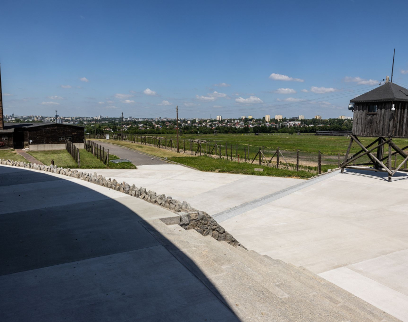 Widok na teren byłego obozu koncentracyjnego na Majdanku os strony Mauzoleum, po prawej budynek Krematorium z wysokim kominem, po lewej wieża strażnica i schody, na drugim planie w oddali zabudowa miejska