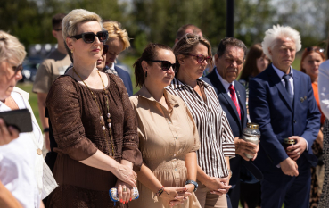 Grupa kobiet w letnich ubraniach i okularach oraz mężczyzn stojących w rzędzie 