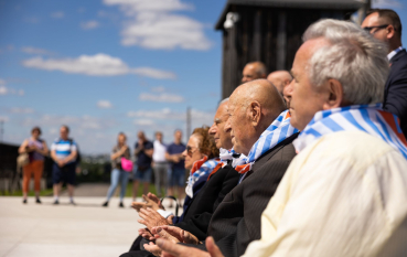 Grupa starszych osób ubrana w biało niebieskie chusty