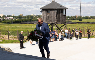 Mężczyzna w garniturze wchodzi po schodach w ręku trzymając wiązankę 