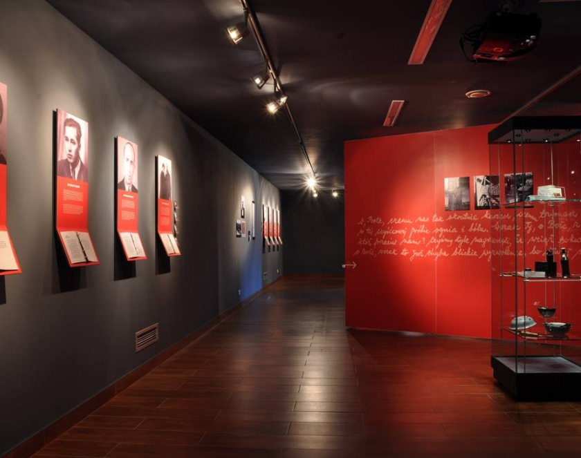 Ekspozycja złożona z czerwonych paneli oraz zdjęć przedstawiających portrety kobiet i mężczyzn