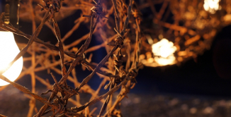 Fragment sfery z drutu kolczastego z żarówką w centrum, dookoła ciemność