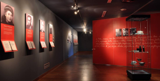 Ekspozycja złożona z czerwonych paneli oraz zdjęć przedstawiających portrety kobiet i mężczyzn