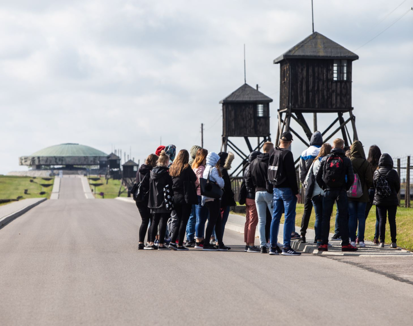 Grupa osób na drodze przy wieży wartowniczej, w tle Pomnik Mauzoleum 