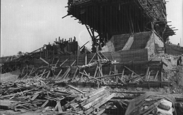 Pomnik - Brama otoczony drewnianym rusztowaniem, na pierwszym planie sterta rozrzuconych połamanych desek