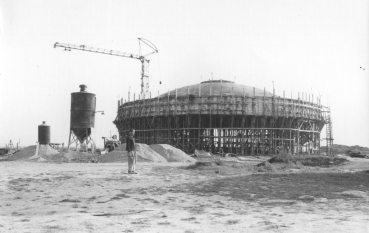 czarno-białe zdjęcie, pomnik Mauzoleum otoczony drewnianym rusztowaniem, po lewej stronie mężczyzna.