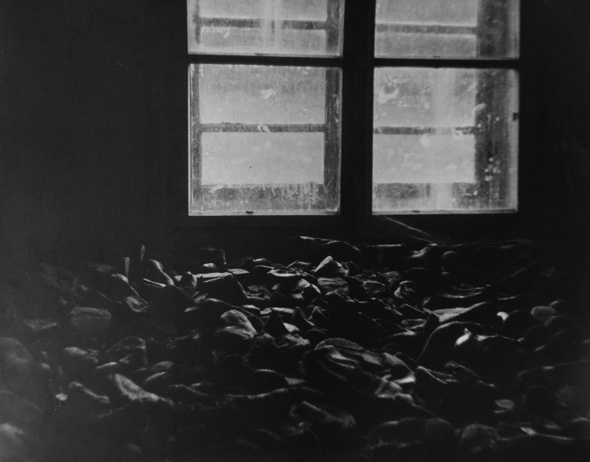 Czarno-białe zdjęcie, stos butów na drugim planie podwójne okno