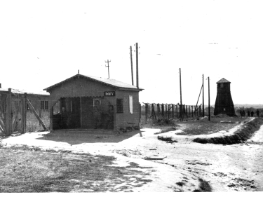 Parterowa budka wartownicza z gankiem pokrytym dachem. Za nią wieżyczka wartownicza