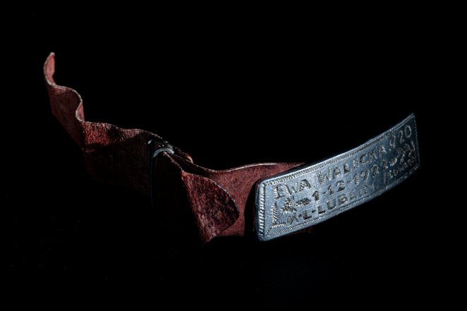 Bransoletka z metalową prostokątną blaszką z inskrypcją: EWA ( reszta napisu nieczytelna). 