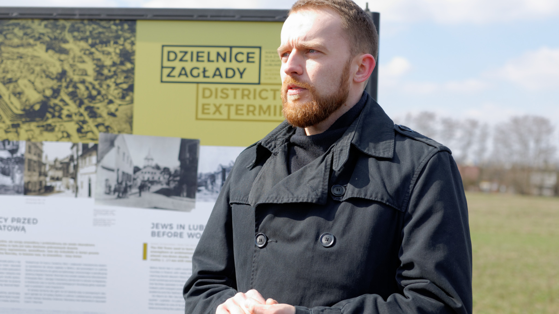 Mężczyzna na tle tablicy z wystawą 