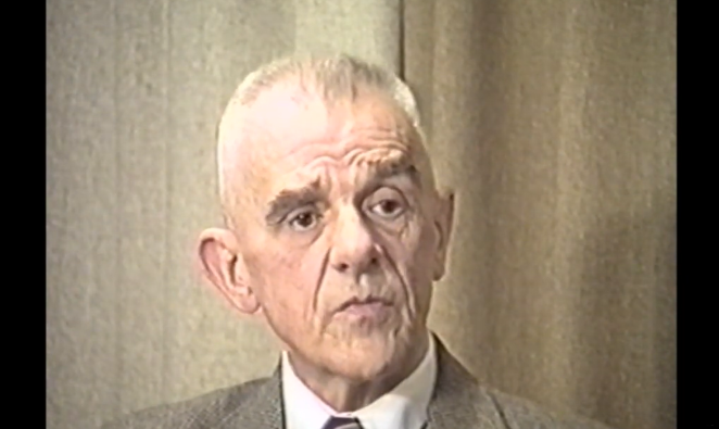 Screen video, starszy mężczyzna ubrany w białą koszulę i melanżową marynarkę