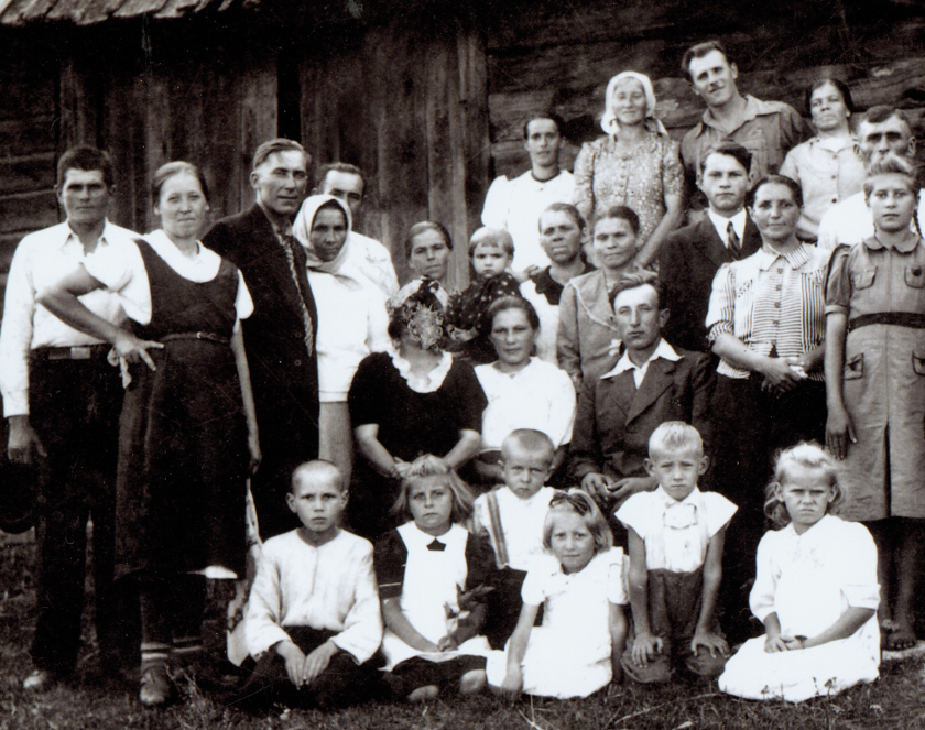 Kilkudziesięcioro osobowy portret rodzinny na tle drewnianej stodoły