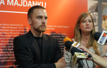 Młoda kobieta o jasnych włosach i rudy mężczyzna z brodą w czarnej marynarce udzielają wywiadu