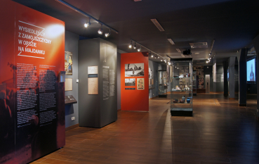 Wnętrze wystawy, panele w kolorze czerwonym oraz przeszkolona gablota