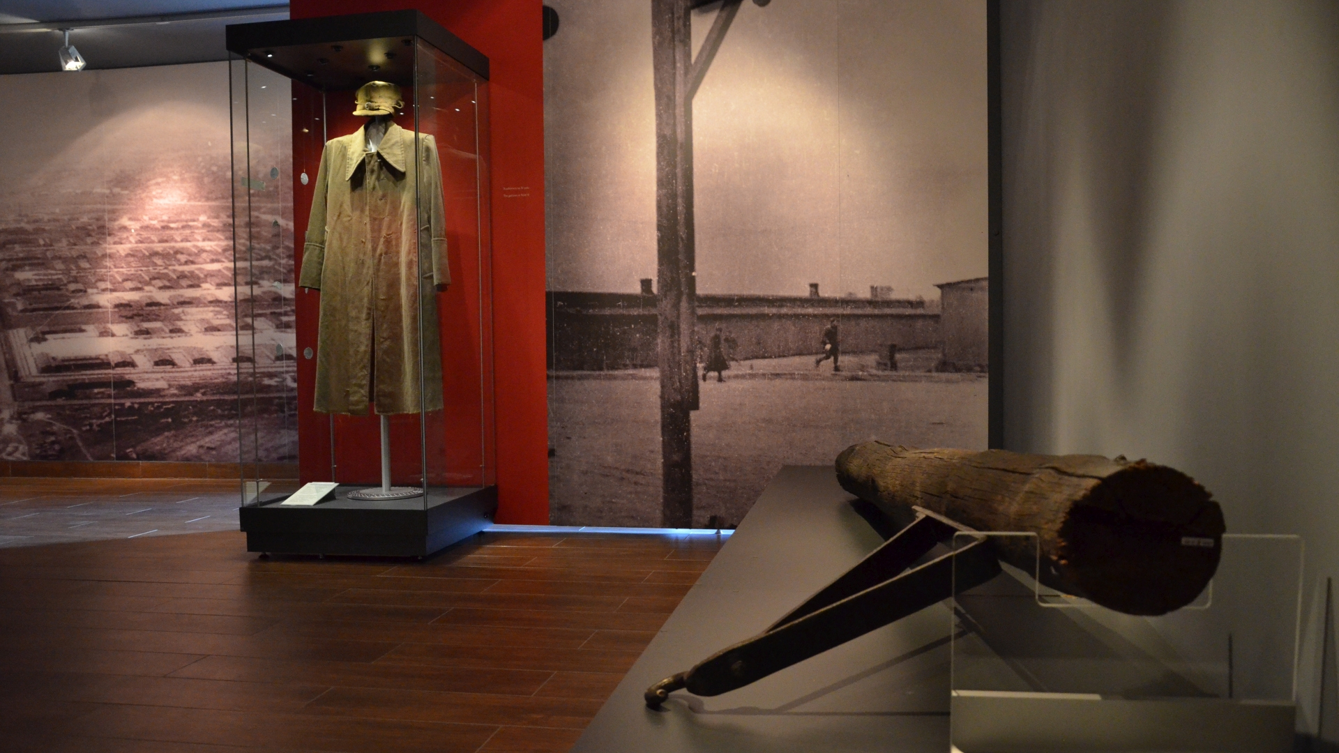 Fragment wystawy, od prawej na ścianie zdjęcie obozu z lotu ptaka, gablota z elementami umundurowania, zdjęcie szubienicy 