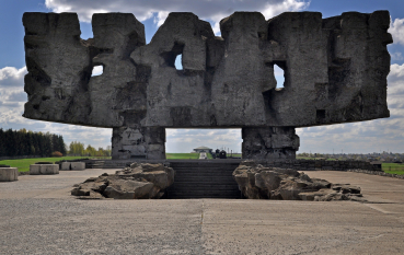 Monumentalna, abstrakcyjna kamienna forma złożona z zespolonych 6 przęseł osadzona na dwóch kamiennych pylonach, pośrodku prostokątny otwórz, poniżej schody prowadzące do wgłębienia w ziemi.