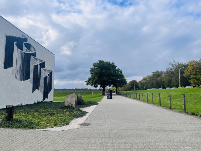 ściana budynku pokryta muralem: 1944, w tle drzewo oraz wystawa plenerowa 