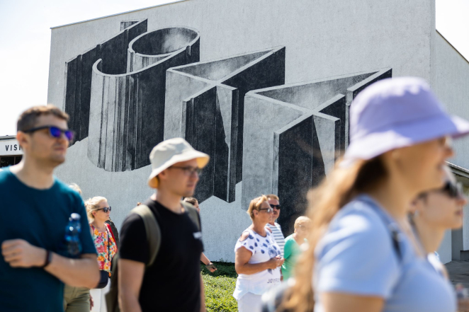 Grupa osób na tle muralu 1944.