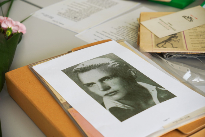 A thick folder with a photo of a young man printed on it, next to some documents. 