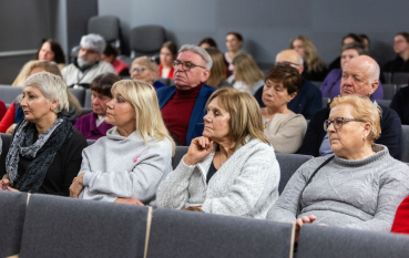 Kilkanaście osób siedzących na sali podczas wydarzenia. 