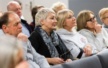 Kilka osób siedzących na sali podczas wydarzenia. 