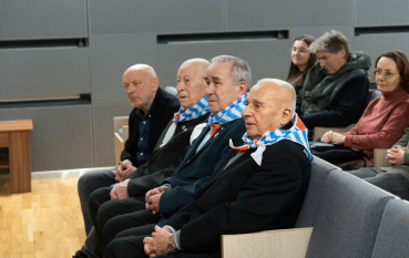 Trzej byli więźniowie w chustach o wzorze biało-niebieskich pasów oraz czerwonym trójkącie oraz Dyrektor Wiesław Wysok. 