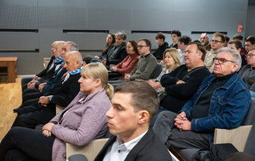 Grupa kilkunastu osób siedzących w sali audytoryjnej, wśród nich byli więźniowie 