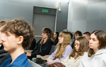 Grupa kilkunastu młodych osób siedzących w sali audytoryjnej 
