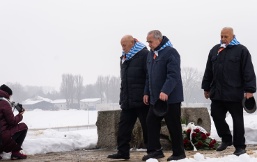 Trzech byłych więźniów składa kwiaty.