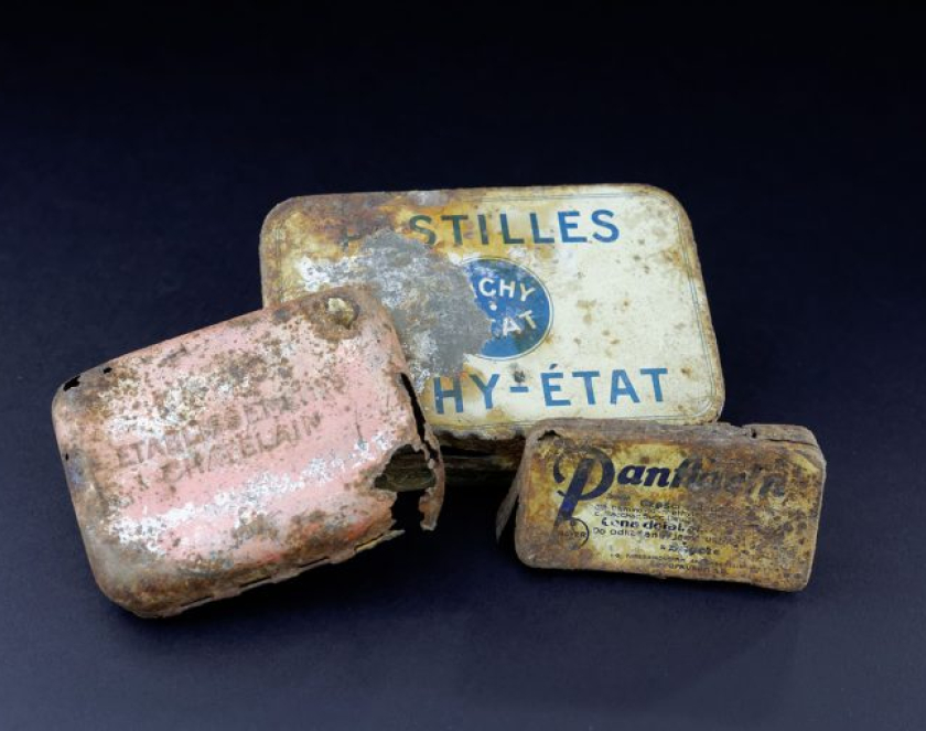 Trzy metalowe opakowania po lekach z nieczytelnymi napisami