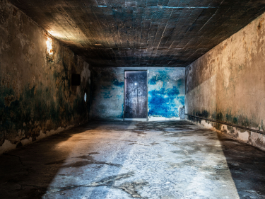 Wnętrze budynku przypominającego bunkier z metalowymi drzwiami, na ścianach duże niebieskie plamy