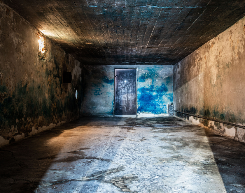 Wnętrze budynku przypominającego bunkier z metalowymi drzwiami, na ścianach duże niebieskie plamy
