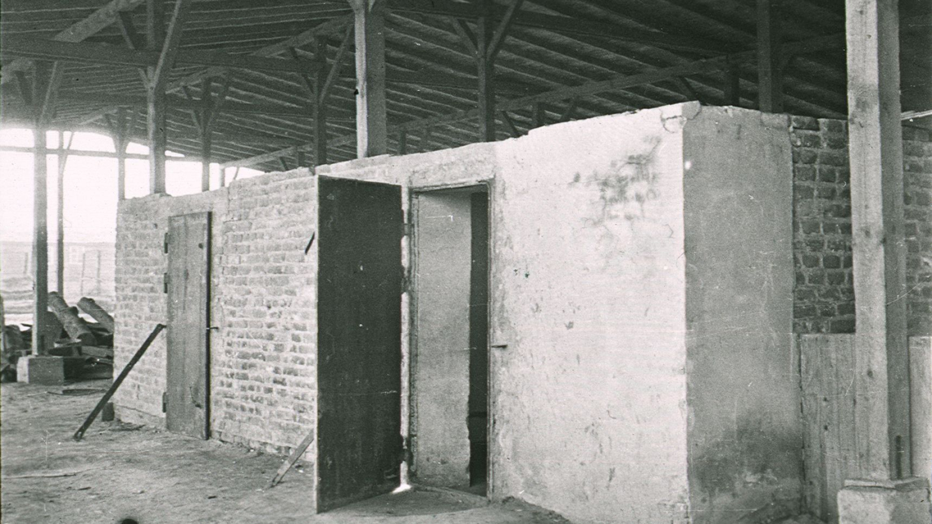 Czarno-białe zdjęcie, betonowa prostokątna zabudowa, dwie pary drzwi, wiata