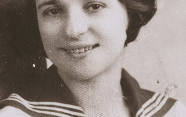 Zdjęcie młodej kobiety z włosami za ucho ubranej w białą bluzkę z ciemnym kołnierzykiem