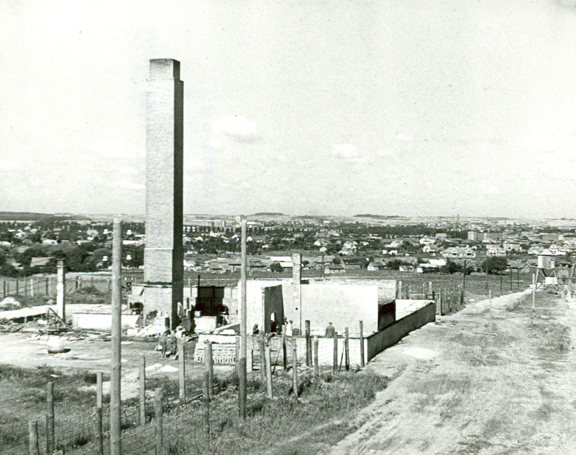 Zdjęcie z murowanymi piecami i kominem na pierwszym tle. Z tyłu pola i domy mieszkalne