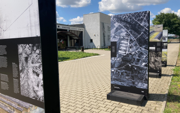 Kilka paneli wystawy, na drugim planie wejście do Centrum Obsługi Zwiedzających 