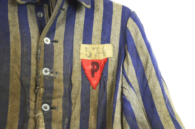 Fragment marynarki więźniarskiej, pasiaka; tkanina w biało niebieskie pasy, na lewej klapie czerwony trójkąt z literą P oraz numer 574. 