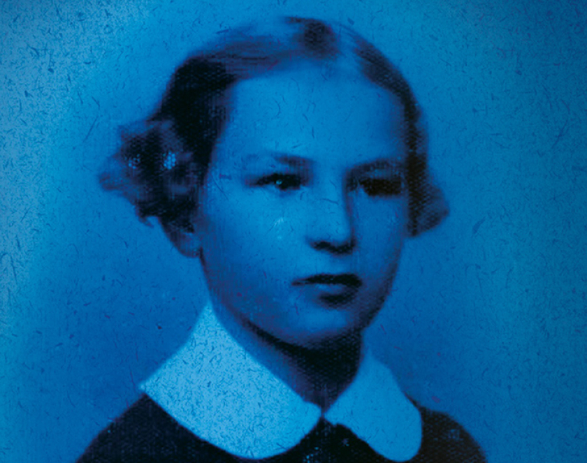 Niebieskie zdjęcie kilkuletniej dziewczyny o włosach upiętych w koszyczki nad uszami 