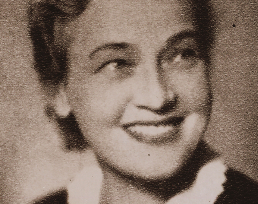 Młoda uśmiechnięta kobieta ubrana w ciemną bluzkę z białym kołnierzykiem 