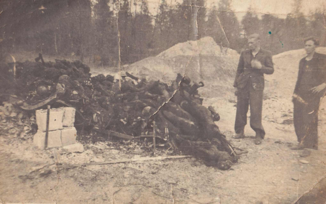 Podniszczone zdjęcie pokazujące spalone fragmenty drewna i metalu. Po prawej stronie dwóch mężczyzn