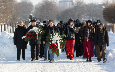 Grupa osób niosących biało-czerwone wiązanki.
