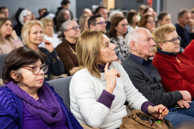 Grupa osób na sali audytoryjnej. 