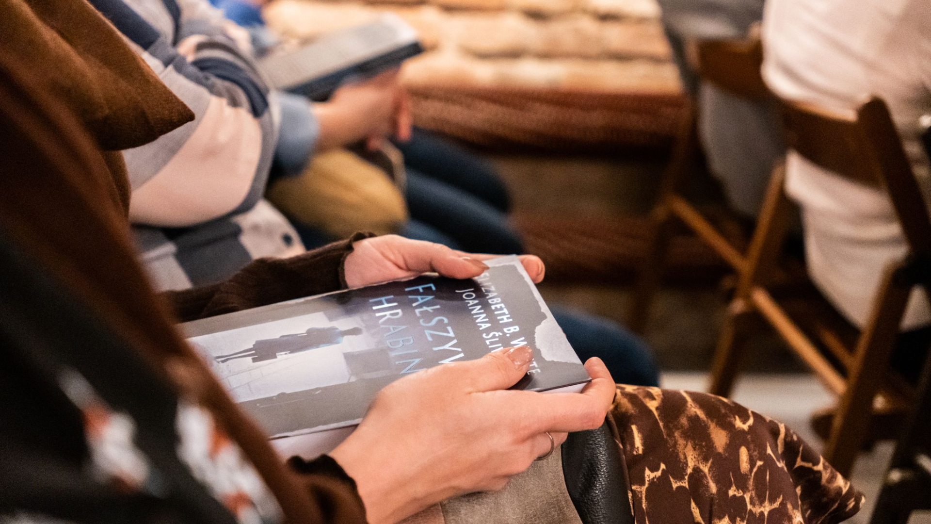 Kobiece dłonie trzymają książkę. Na okładce widoczny napis: Fałyszwa Hrabina.