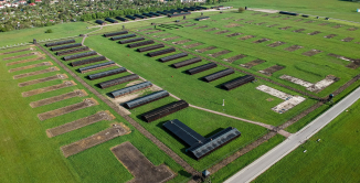 Zdjęcie z lotu ptaka, na pierwszym planie planie rzędy baraków oraz ich pozostałości, na drugim zabudowa miejska 