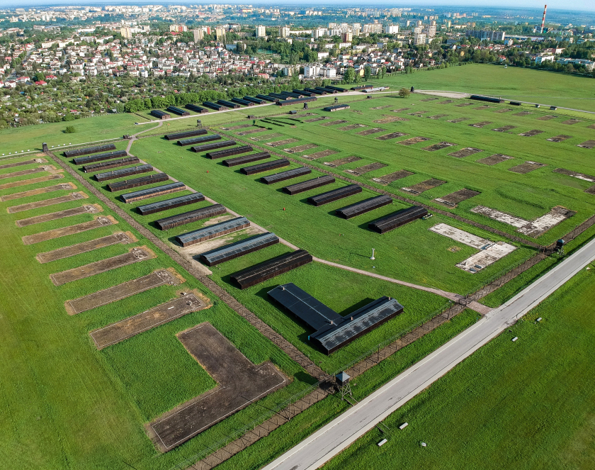 Zdjęcie z lotu ptaka, na pierwszym planie planie rzędy baraków oraz ich pozostałości, na drugim zabudowa miejska 