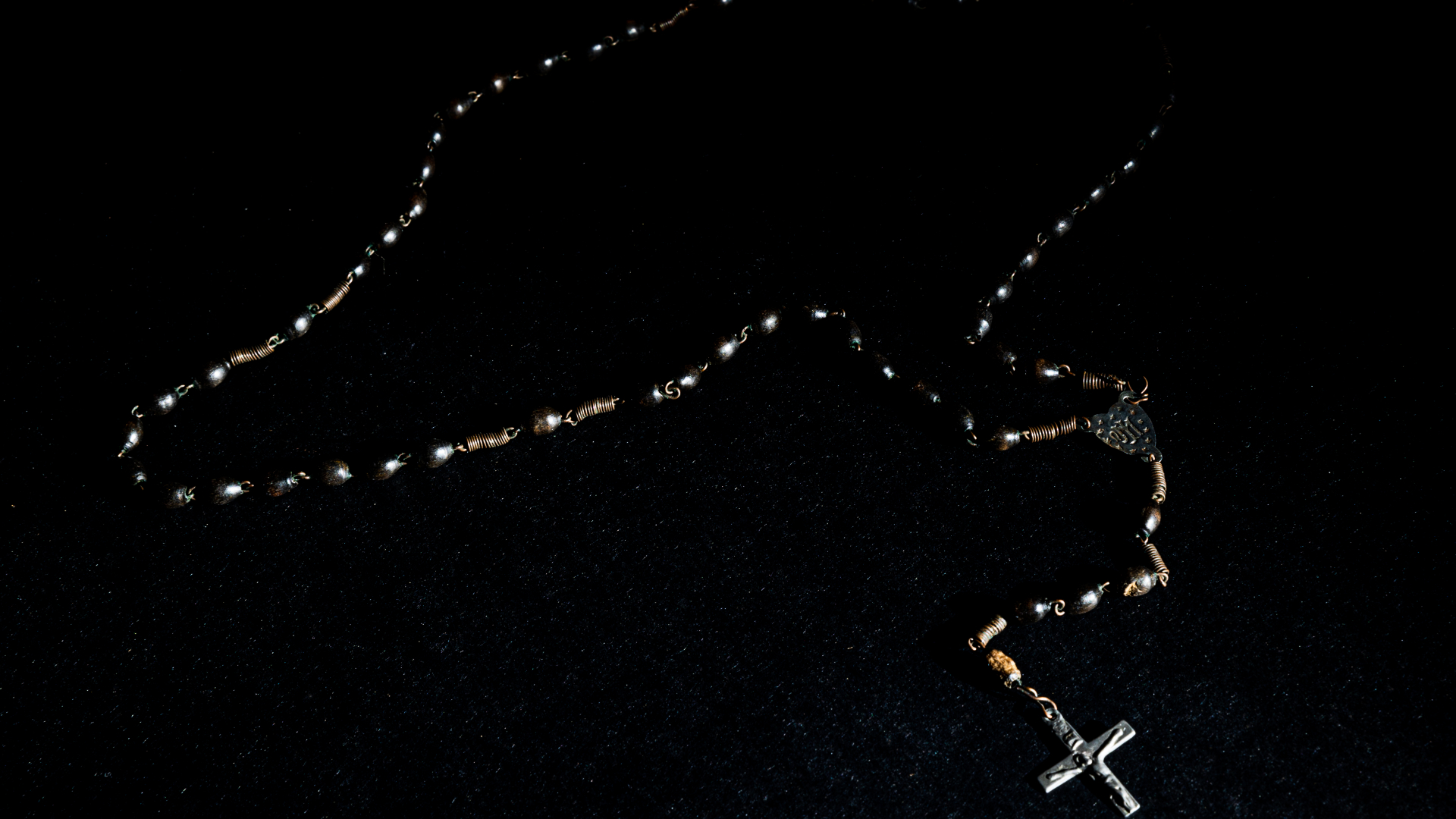 Różaniec złożony z czarnych paciorków na czarnym tle