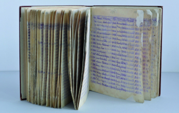 Otwarta książka, widoczne wpisy odręczne granatowym atramentem 