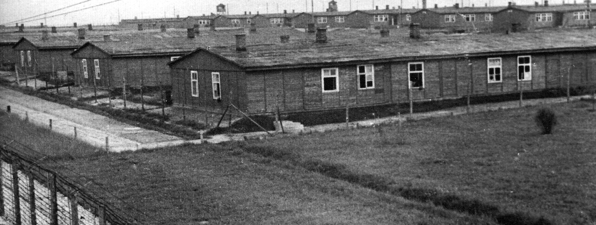 Kilka baraków więźniarskich z oknami oraz ogrodzenie z drutu kolczastego 