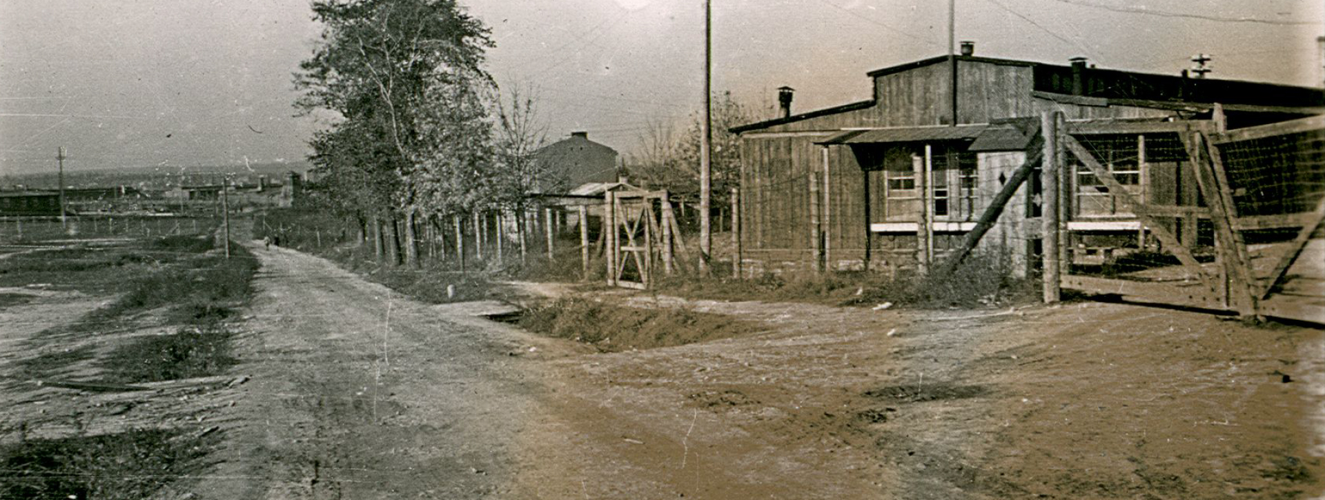 Uklepana ziemia w formę drogi, po prawej barak więźniarski oraz zamknięta brama 